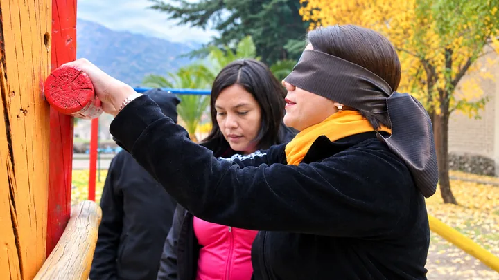 Dos participantes colaboran en una dinámica con los ojos vendados al aire libre
