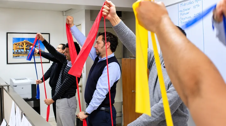 Equipo de trabajo realiza una actividad guiada con bandas elásticas en la oficina