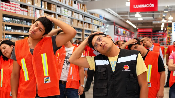 Trabajadores de una tienda realizan una pausa de movimiento guiada