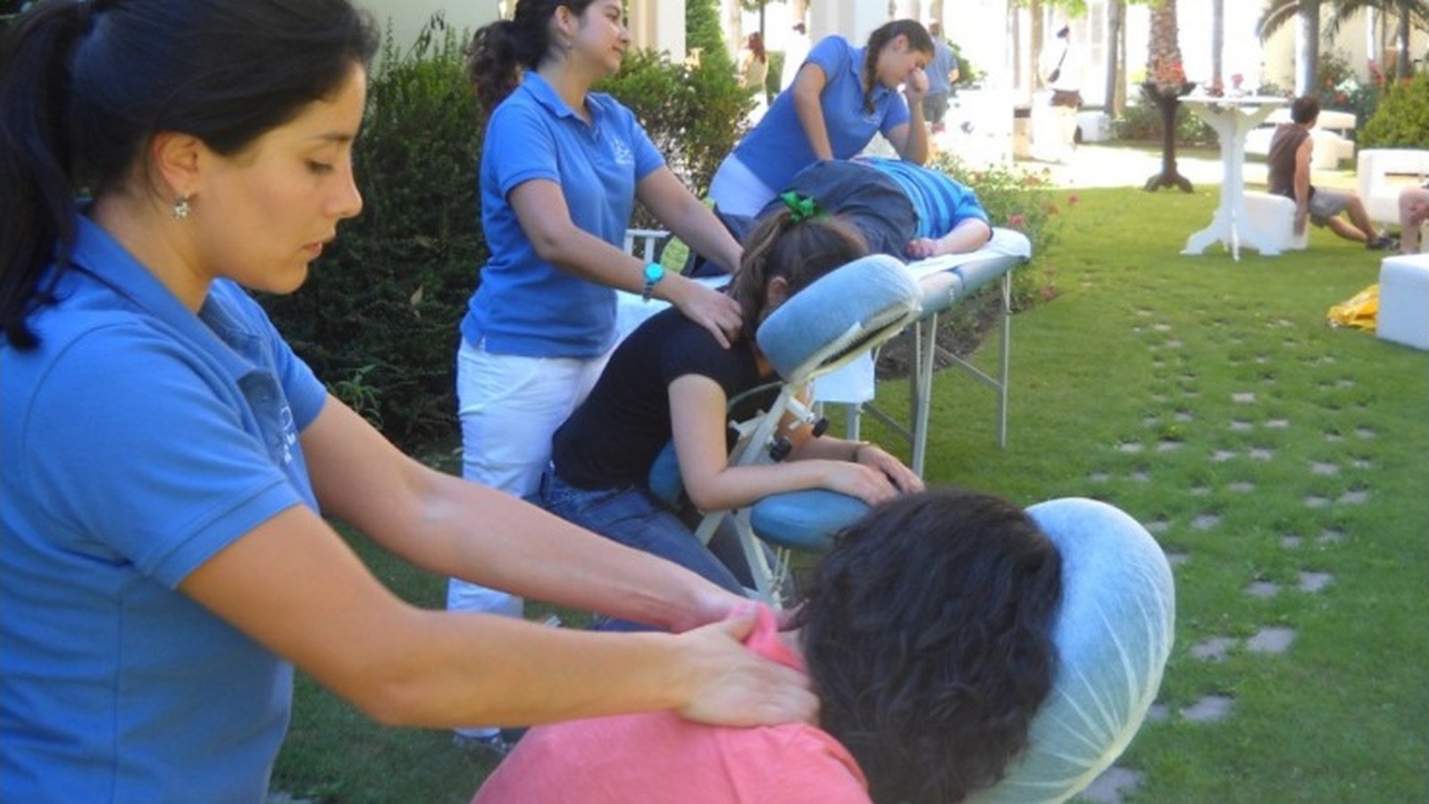 Terapeutas realizan masajes en sillas durante una actividad de bienestar al aire libre